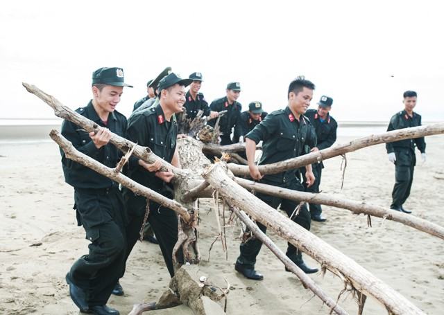 Các chiến sĩ Trung đoàn Cảnh sát cơ động Bắc Trung Bộ hợp sức giải phóng một cây gỗ lớn án ngữ trên bãi biển sau bão